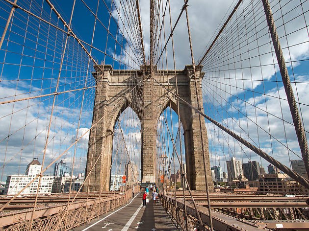 Brooklyn Bridge:
      The Brooklyn Bridge is a hybrid cable-stayed/suspension bridge in New York City and is one of the oldest bridges in the United States. Started in 1869 and completed fourteen years later in 1883, it connects the boroughs of Manhattan and Brooklyn by spanning the East River. It has a main span of 1,595.5 feet (486.3 m) and was the first steel-wire suspension bridge constructed. It was originally called the New York and Brooklyn Bridge and the East River Bridge, but it was later dubbed the Brooklyn Bridge, a name coming from an earlier January 25, 1867, letter to the editor of the Brooklyn Daily Eagle and formally so named by the city government in 1915. Since opening, it has become an icon of New York City and was designated a National Historic Landmark in 1964 and a National Historic Civil Engineering Landmark in 1972.